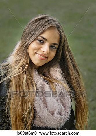 Stock Image - Portrait of long haired young woman weraing snood looking at camera smiling. Fotosearch