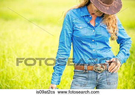 "Portrait of mature woman, standing in field, wearing denim shirt, jeans and cowboy hat" View Large Photo Image Stock Photograph - "Portrait of mature woman, standing in field, wearing denim shirt, jeans and cowboy hat". Fotosearch