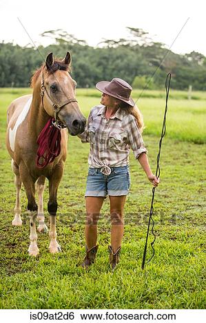 Stock Photograph - Portrait of mature woman standing beside horse. Fotosearch
