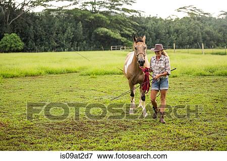 Stock Photo - Portrait of mature woman walking with horse in field. Fotosearch
