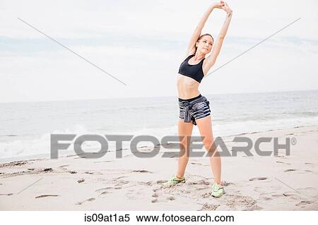 "Portrait of mid adult woman standing on beach, hands over head, stretching" View Large Photo Image Stock Photography - "Portrait of mid adult woman standing on beach, hands over head, stretching". Fotosearch
