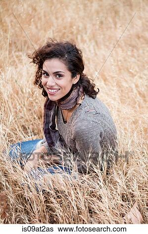 Portrait of young woman sitting in long grass View Large Photo Image Stock Photograph - Portrait of young woman sitting in long grass. Fotosearch