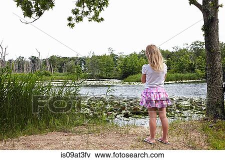 Stock Photo - Rear of girl looking out over rural lake. Fotosearch