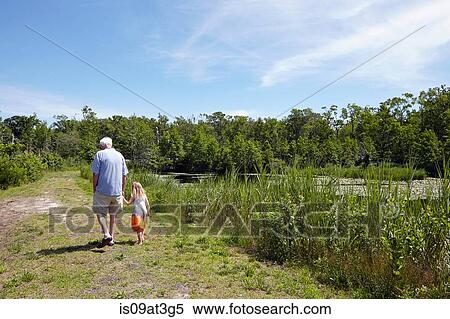 Rear view of girl and grandfather strolling at rural lake View Large Photo Image Stock Photography - Rear view of girl and grandfather strolling at rural lake. Fotosearch