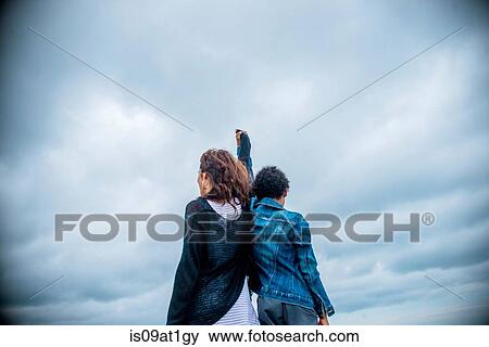 Rear view of mature woman and son shoulder to shoulder against overcast sky View Large Photo Image Stock Photo - Rear view of mature woman and son shoulder to shoulder against overcast sky. Fotosearch