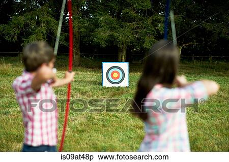 Rear view of teenage brother and sister practicing archery View Large Photo Image Stock Photography - Rear view of teenage brother and sister practicing archery. Fotosearch