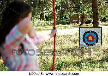 Rear view of teenage girl practicing archery with target View Large Photo Image Stock Photograph - Rear view of teenage girl practicing archery with target. Fotosearch