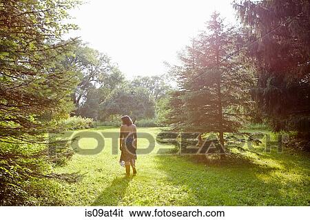 Rear view of woman strolling in sunlit park View Large Photo Image Stock Photograph - Rear view of woman strolling in sunlit park. Fotosearch