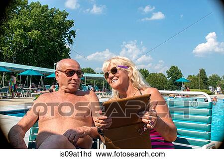 Senior couple looking at digital tablet at outdoor swimming pool View Large Photo Image Stock Image - Senior couple looking at digital tablet at outdoor swimming pool. Fotosearch