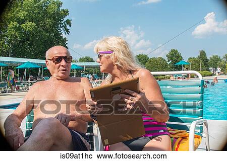 Senior couple using digital tablet at outdoor swimming pool View Large Photo Image Stock Image - Senior couple using digital tablet at outdoor swimming pool. Fotosearch