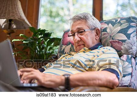 Stock Image - "Senior man, sitting at home, using laptop". Fotosearch