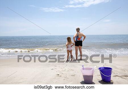 Senior woman with granddaughter with hands on hips looking out from beach View Large Photo Image Stock Image - Senior woman with granddaughter with hands on hips looking out from beach. Fotosearch