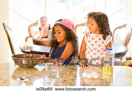Sisters at kitchen counter whisking choclate cake mix in mixing bowl looking down smiling View Large Photo Image Stock Image - Sisters at kitchen counter whisking choclate cake mix in mixing bowl looking down smiling. Fotosearch