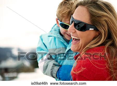 Stock Image - Skiing mother carrying toddler son. Fotosearch