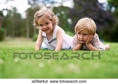 Surface level of boy and girl lying on grass View Large Photo Image Stock Photograph - Surface level of boy and girl lying on grass. Fotosearch