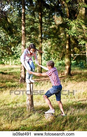 Teenage brother and sister balancing on top of fence post View Large Photo Image Stock Image - Teenage brother and sister balancing on top of fence post. Fotosearch