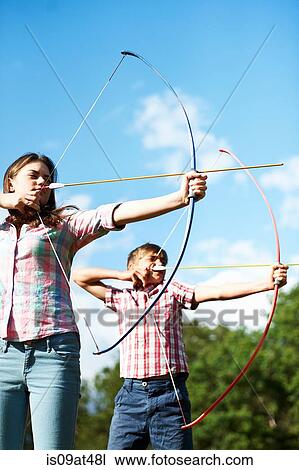 Stock Image - Teenage brother and sister practicing archery. Fotosearch