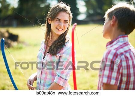 Teenage girl talking to brother whilst practicing archery View Large Photo Image Picture - Teenage girl talking to brother whilst practicing archery. Fotosearch