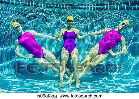 Stock Image - "Three female swimmers, underwater, holding hands". Fotosearch