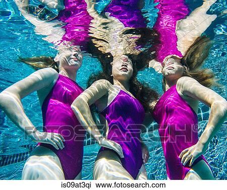 Stock Image - "Three female swimmers, underwater, hands on hips". Fotosearch