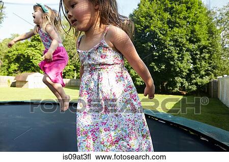 Two girls jumping on trampoline in garden View Large Photo Image Stock Image - Two girls jumping on trampoline in garden. Fotosearch