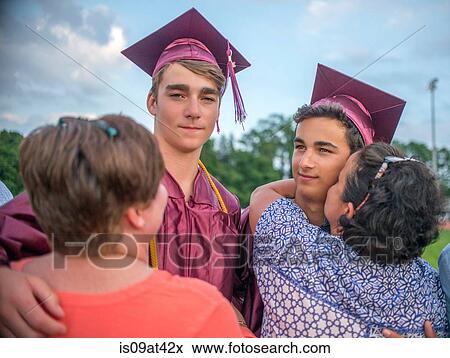 Stock Photo - Two young men hugging family at graduation ceremony. Fotosearch