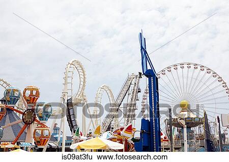 View of amusement park with rollercoaster and ferris wheel View Large Photo Image Stock Photograph - View of amusement park with rollercoaster and ferris wheel. Fotosearch