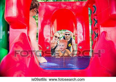 View through playground equipment of mother and father encouraging baby boy View Large Photo Image Stock Photograph - View through playground equipment of mother and father encouraging baby boy. Fotosearch