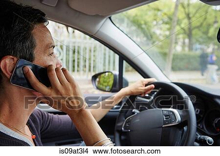 Picture - "Woman driving car, using smartphone". Fotosearch