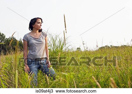 Stock Image - Woman looking out from field of long grass. Fotosearch