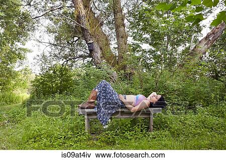 Woman lying on rural bench View Large Photo Image Stock Photo - Woman lying on rural bench. Fotosearch