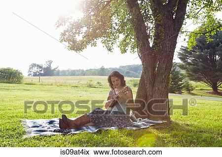 Woman on picnic blanket in field playing ukuele View Large Photo Image Stock Photo - Woman on picnic blanket in field playing ukuele. Fotosearch