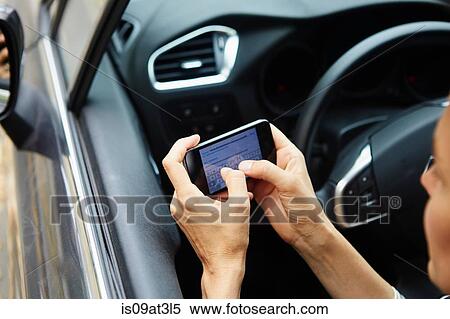 Stock Photography - "Woman sitting in car, texting on smartphone". Fotosearch