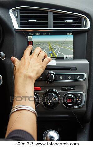 Stock Image - "Woman sitting in car, using gps, focus on hand". Fotosearch