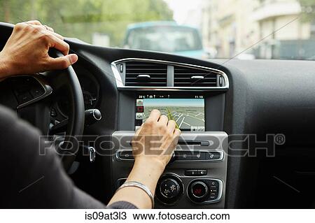 Stock Image - "Woman sitting in car, using gps, focus on hands". Fotosearch