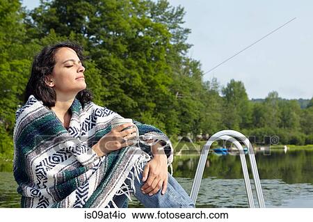 "Woman wrapped in blanket sitting on lakeside, New Milford, Pennsylvania, USA" View Large Photo Image Picture - "Woman wrapped in blanket sitting on lakeside, New Milford, Pennsylvania, USA". Fotosearch