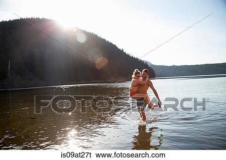 Stock Photograph - "Young couple in lake, man carrying woman, Lost Lake, Oregon, USA". Fotosearch