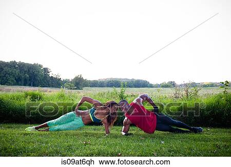 Stock Image - Young couple training doing side push ups in unity. Fotosearch