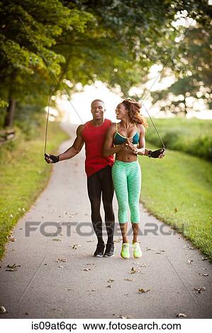 Stock Image - Young couple training on path skipping in unity. Fotosearch