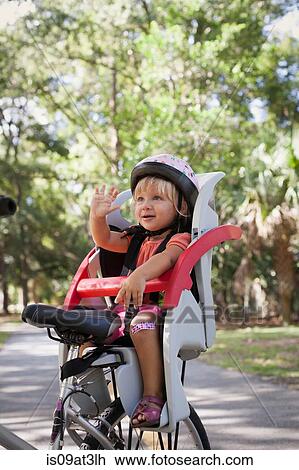 Stock Image - "Young girl sitting in child's bicycle seat, enjoying journey". Fotosearch