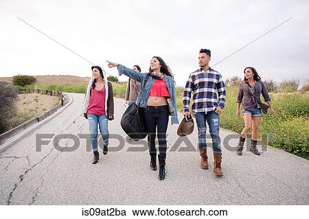 Stock Image - Young man and four adult sisters walking along rural road. Fotosearch