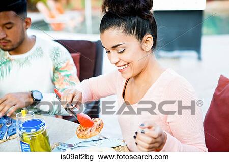 Stock Image - Young man and sister having family barbecue lunch on patio. Fotosearch