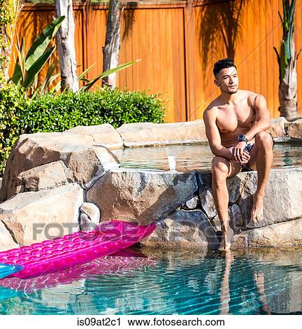 Young man sitting on garden swimming pool rocks View Large Photo Image Stock Image - Young man sitting on garden swimming pool rocks. Fotosearch