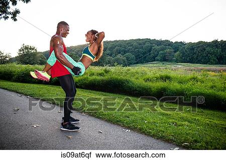 Stock Image - Young woman doing sit up training whilst straddling boyfriend. Fotosearch