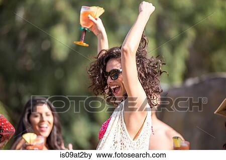 Young woman drinking cocktail and dancing in garden View Large Photo Image Stock Photo - Young woman drinking cocktail and dancing in garden. Fotosearch