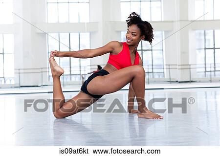 "Young woman in dance studio stretching leg, looking away smiling" View Large Photo Image Stock Photograph - "Young woman in dance studio stretching leg, looking away smiling". Fotosearch