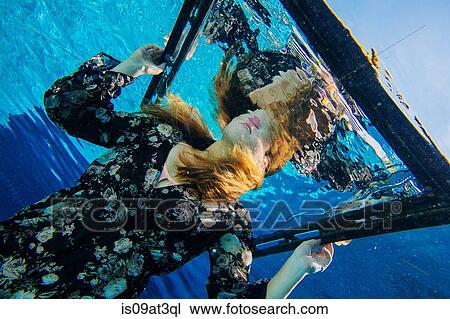 Stock Image - "Young woman, underwater, holding frame". Fotosearch