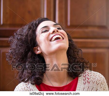 Stock Image - Young woman with head back laughing. Fotosearch
