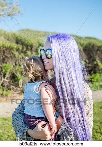 Stock Photograph - "Young woman with long purple hair, holding baby daughter". Fotosearch