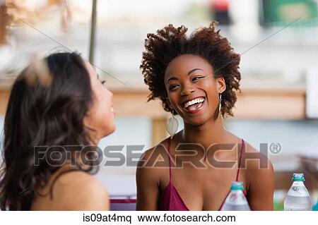 Stock Photography - Young women chatting on bench. Fotosearch
